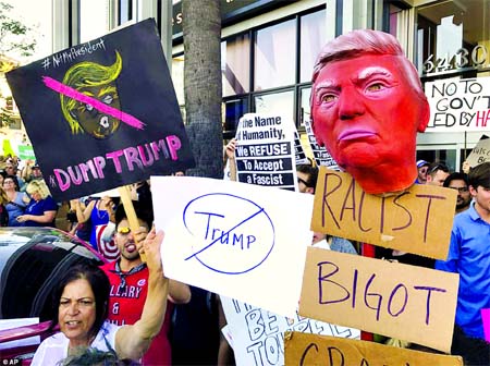 Anti-Donald Trump protesters continued to rally across the country Sunday to disavow the president-elect. Some of them are pictured holding signs outside the CNN studios in Los Angeles, California.