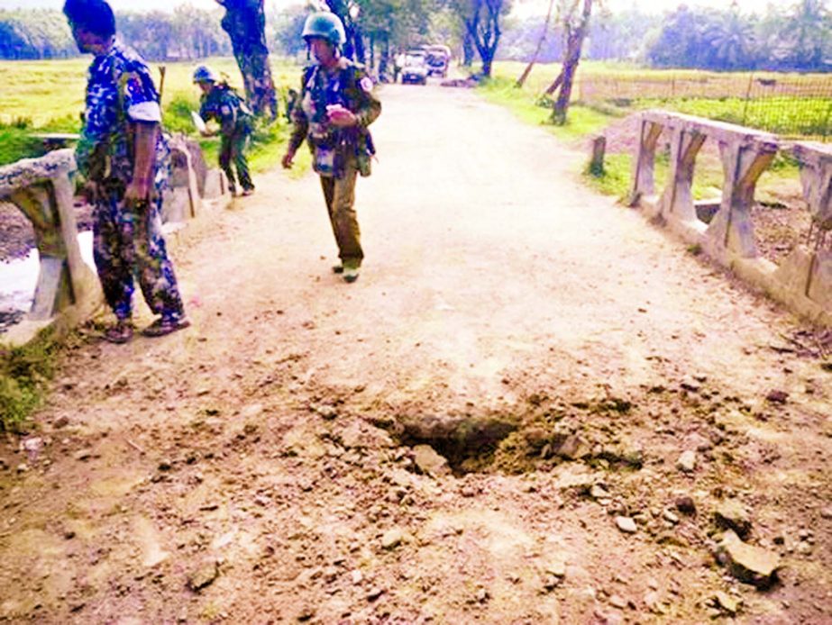 In this photograph released by the Myanmar Armed Forces, soldiers view the crater from a landmine explosion on a bridge in Maung Nama Taung village of Maungdaw, located in Rakhine State near the Bangladesh border.
