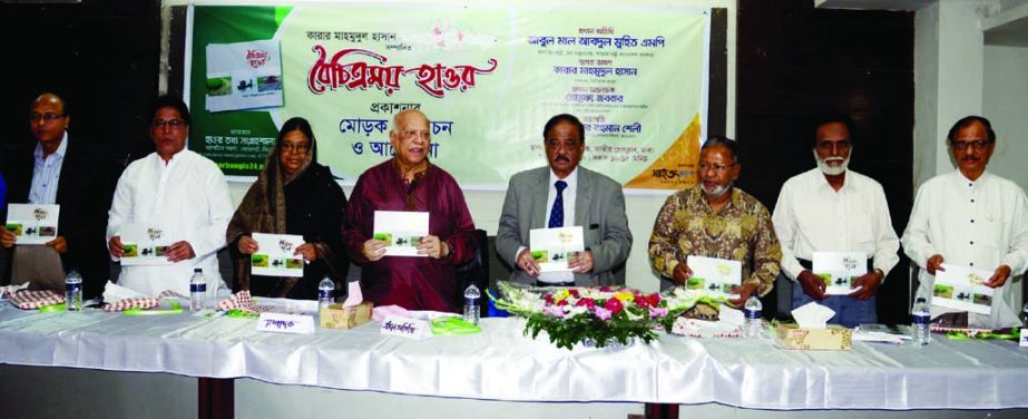 Finance Minister Abul Maal Abdul Muhith along with others holds the copies of a book titled 'Boichitramoy Haor' edited by Mahmudul Hasan at its cover unwrapping ceremony organised by Haor Tathya Sangrahashala at the Jatiya Press Club on Saturday.