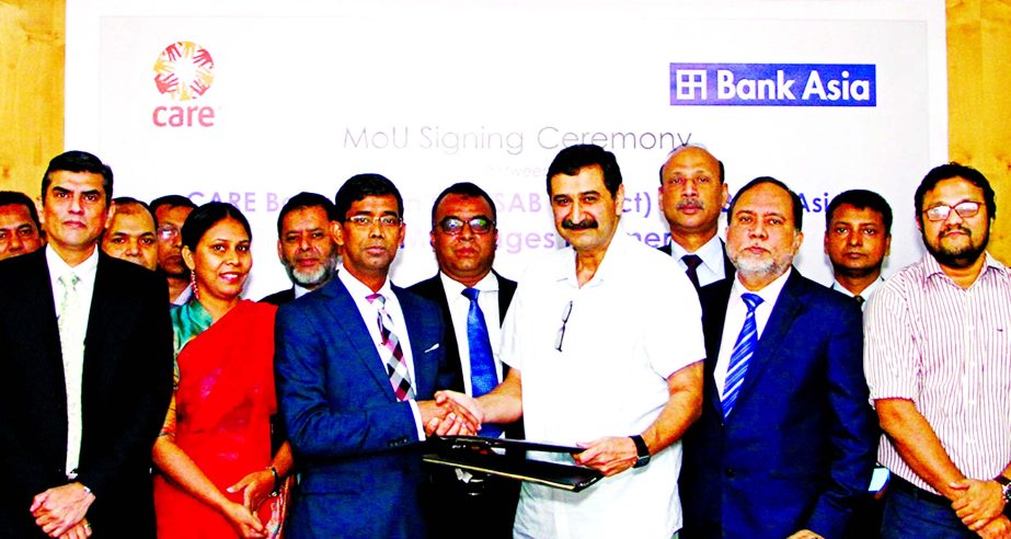 Md Arfan Ali, President and Managing Director of Bank Asia Ltd and Arshad Muhammad, Acting Country Director of CARE Bangladesh exchanging documents after signed a MoU at the banks Corporate Office in the city on Thursday. Mohammad Zahirul Alam and Mian Qu