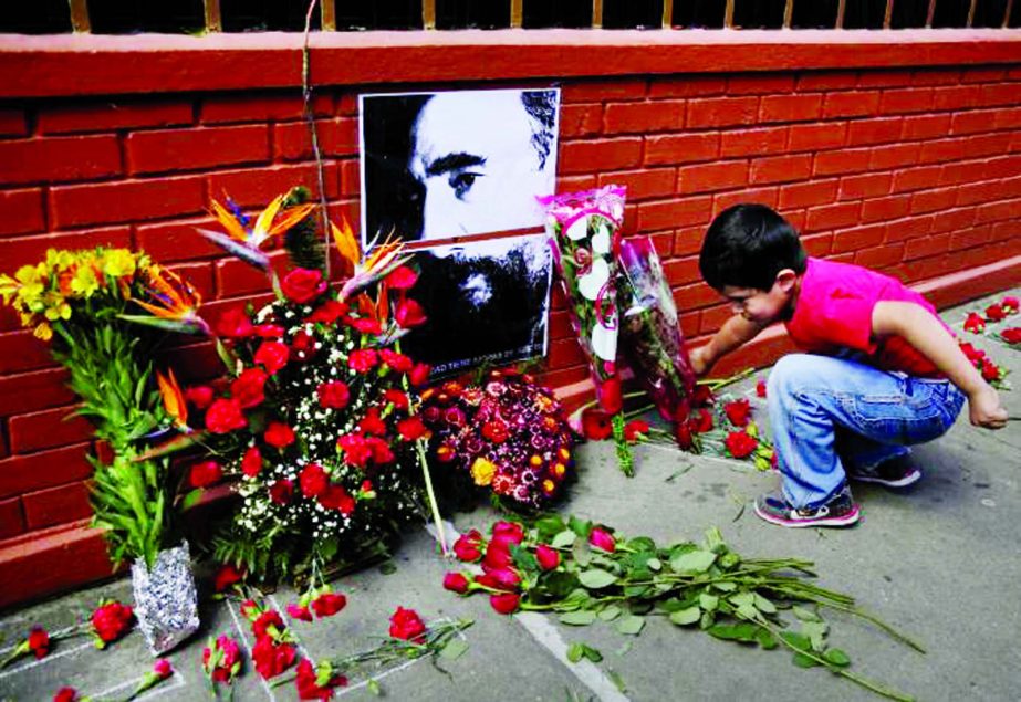 A boy places flowers beside a picture of the late Fidel Castro, as part a tribute outside the Cuban Embassy in Guatemala City following the announcement of the death of Cuban revolutionary leader Fidel Castro.