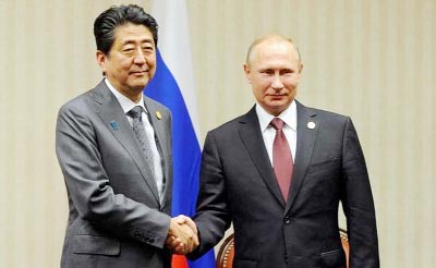 Russian President Vladimir Putin shaking hands with Japanese Prime Minister Shinzo Abe at function.