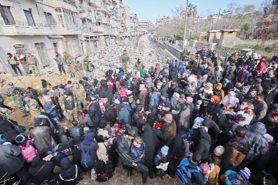 Syrian residents fleeing the violence gather at a checkpoint, manned by pro-government forces, in the Maysaloun neighbourhood of the northern embattled Syrian city of Aleppo on Thursday.