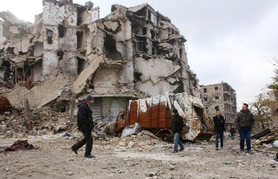 Syrians walk along a destroyed street in the old city of Aleppo on Saturday as pro-government forces re-open roads that were barricaded to divide rebel and government-held areas