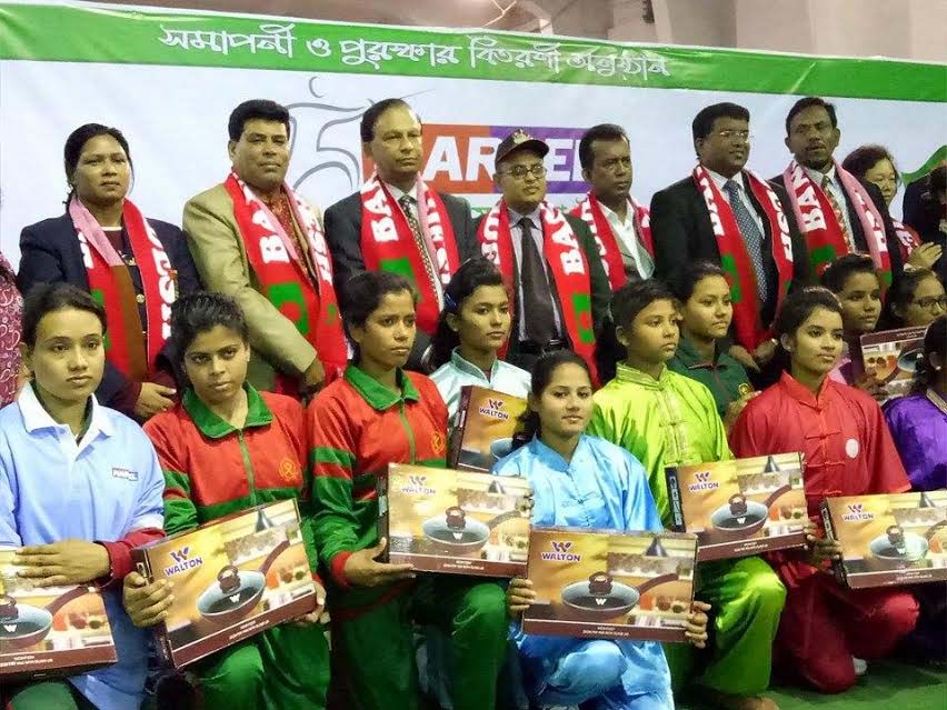The winners of the Marcel 1st National Women's Wushu Competition with the guests and officials of Bangladesh Wushu Association pose for a photo session at the gymnasium of National Sports Council on Wednesday.