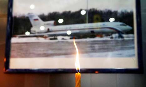 A candle is placed in front of a picture of Tu-154 plane, to commemorate passengers and crew members of Russian military plane, which crashed into the Black Sea on its way to Syria on Sunday.