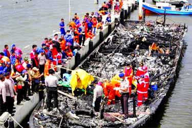 Police and rescue workers search a boat for victims at Muara Angke port in Jakarta, Indonesia.