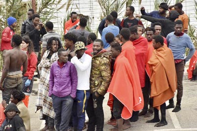 Migrants pictured on the ground in El Tarajal, Ceuta, close to the border with Morocco after being rounded up by police to be attended to by Red Cross personnel