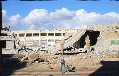 A Syrian boy runs past the rubble of destroyed buildings in the rebel-held area of Daraa in southern Syria.