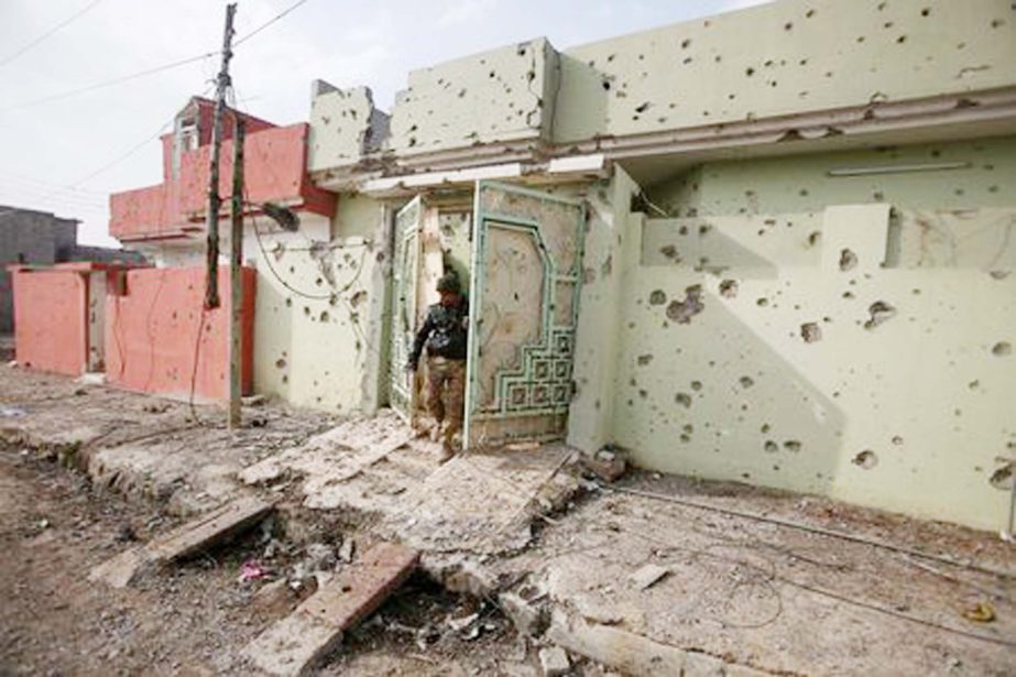 A member of Iraqi security forces inspects a house in the Intisar district of eastern Mosul.