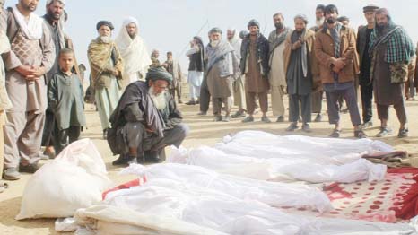 Afghan villagers gather on around several victims' bodies who were killed in US air strike .