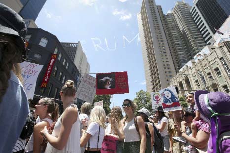 Thousands file through the streets during the Women's March protesting the start of Donald Trump's presidency as a skywriting plane spells out "Trump" above in Sydney, Australia on Saturday.
