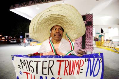 Martin Macias holds a placard against US Republican presidential nominee Donald Trump while standing at Paso del Norte international border crossing bridge in Ciudad Juarez, Mexico