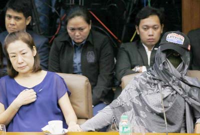 Choi Kyung-jin, left, the widow of South Korean businessman Jee Ick-joo, who was kidnapped and later killed by his abductors, holds hands with their former househelp Marissa Morquicho at the start of the Philippine Senate probe in the killing on Thursday,
