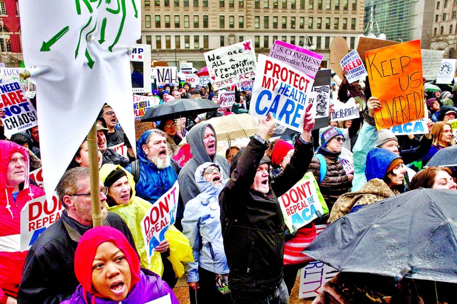 Protesters hold signs and chant in Thomas Paine Plaza to protest President Trump's visit at a GOP retreat in downtown Philadelphia on Thursday.