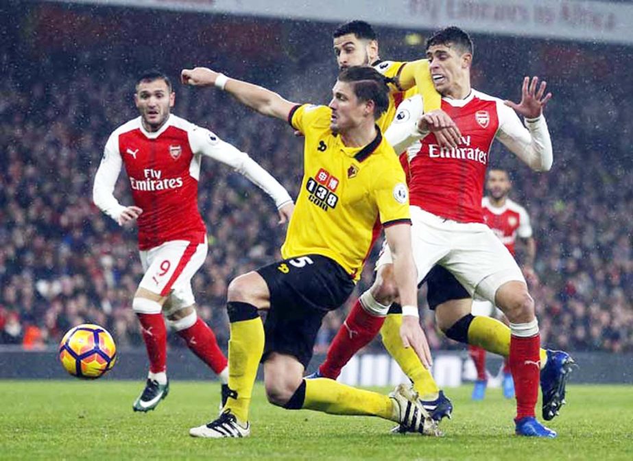 Arsenal's Gabriel (right) and Watford's Sebastian Proedl (center) challenge for the ball during the English Premier League soccer match between Arsenal and Watford at the Emirates stadium in London on Tuesday.