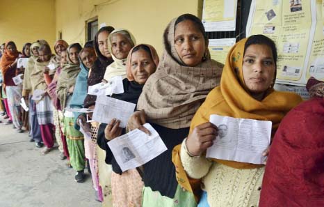 Indian women display their election identity cards as they stand in a queue to cast their votes outside a polling station, at Chogawan village, about 20 kilometers from Amritsar, in the northern Indian state of Punja on Saturday