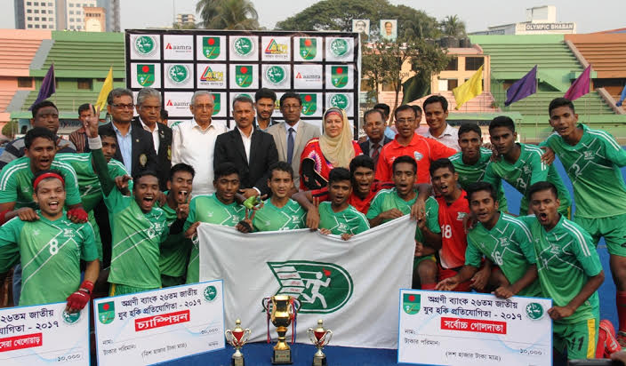Members of BKSP, the champions of the Agrani Bank 26th National Youth Hockey Competition and the guests and officials of Bangladesh Hockey Federation pose for a photo session at the Moulana Bhashani National Hockey Stadium on Monday.