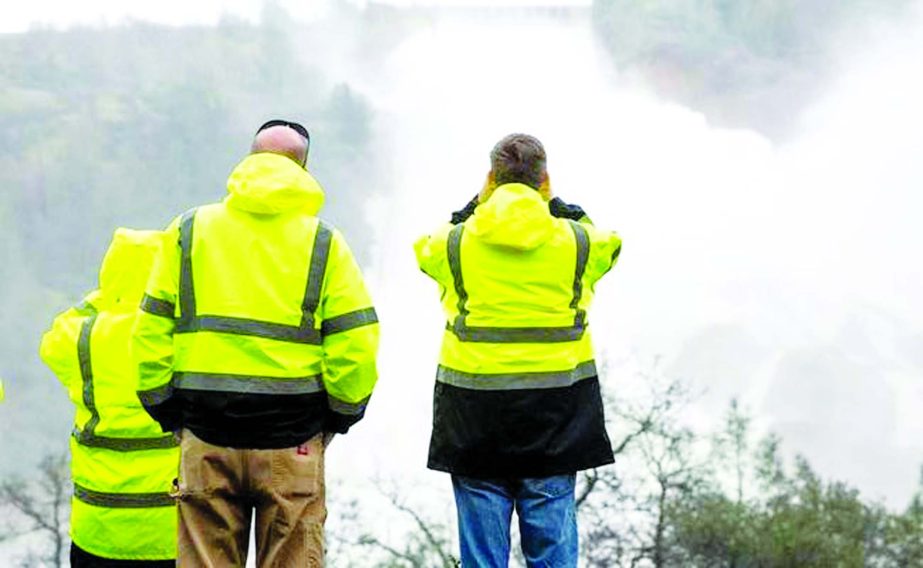 California officials monitor water flowing through a damaged spillway on the Oroville Dam.