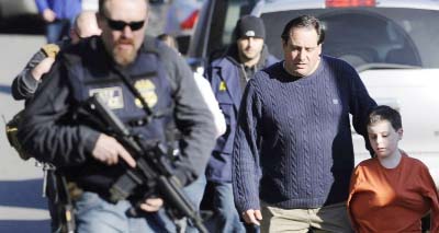 Parents leave a staging area after being reunited with their children following a shooting at the Sandy Hook.