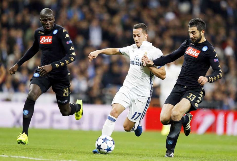 Real Madrid's Lucas Vazquez runs with the ball between Napoli's Kalidou Koulibaly (left) and Napoli's Raul Albiol during the Champions League round of 16, first leg, soccer match between Real Madrid and Napoli at the Santiago Bernabeu stadium in Madrid