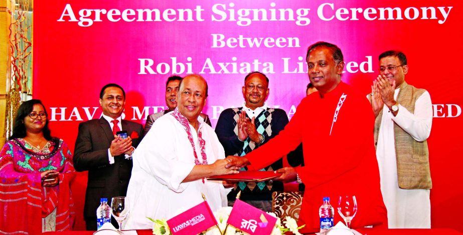 Mahtab Uddin Ahmed, Managing Director and CEO of Robi and Faridur Reza Sagar, Chairman, HAVAS Media Bangladesh, exchanging documents after signing a media agency deal at a city hotel on Saturday. High officials of both the organisations were also present