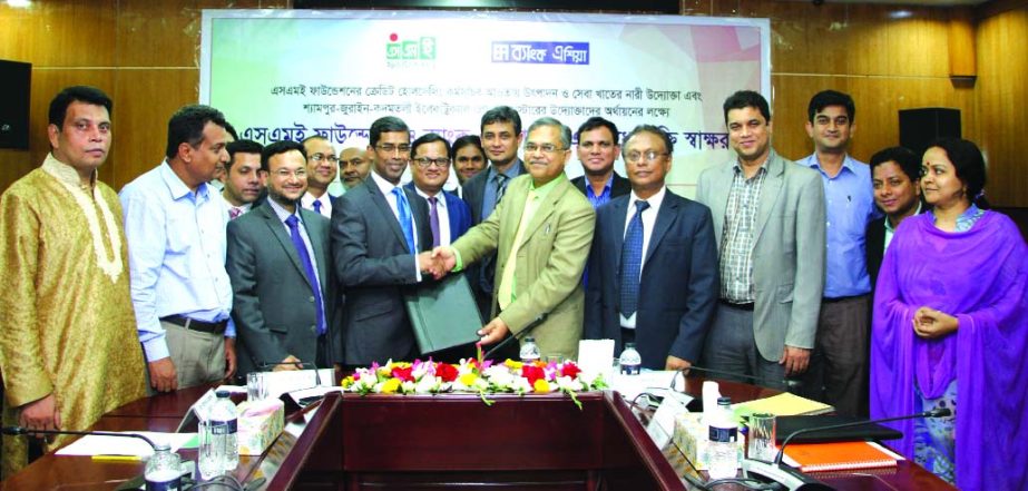 Md Arfan Ali, Managing Director of Bank Asia and Shafiqul Islam, Managing Director of SME Foundation exchanging documents after signing an agreement on facilitating financial support to women entrepreneurs and cluster of electrical product at a function i