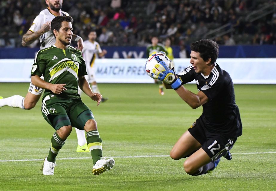 Los Angeles Galaxy goalkeeper Brian Rowe, right, stops a shot by Portland Timbers midfielder Sebastian Blanco during the first half of a preseason MLS soccer match in Los Angeles on Saturday.
