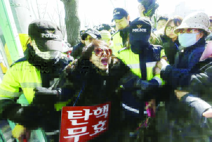 A supporter of impeached South Korean President Park Geun-hye is detained by police officers during a rally opposing her impeachment as the Constitutional Court holds its final hearing in the impeachment trial of Park in front of the court in Seoul on Mon