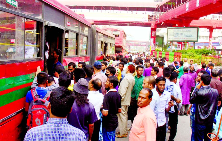 Due to non-availability of buses during transport workers' sudden nationwide strike, people including students rush at the bus stand to get into a bus risking their life on Wednesday.