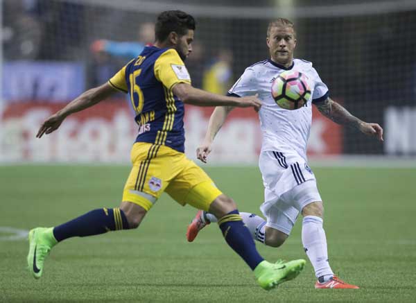 New York Red Bulls' Sal Zizzo (left) kicks the ball away from Vancouver Whitecaps' Marcel de Jong during the first half of a CONCACAF Champions League soccer quarterfinal in Vancouver, British Columbia, on Thursday.