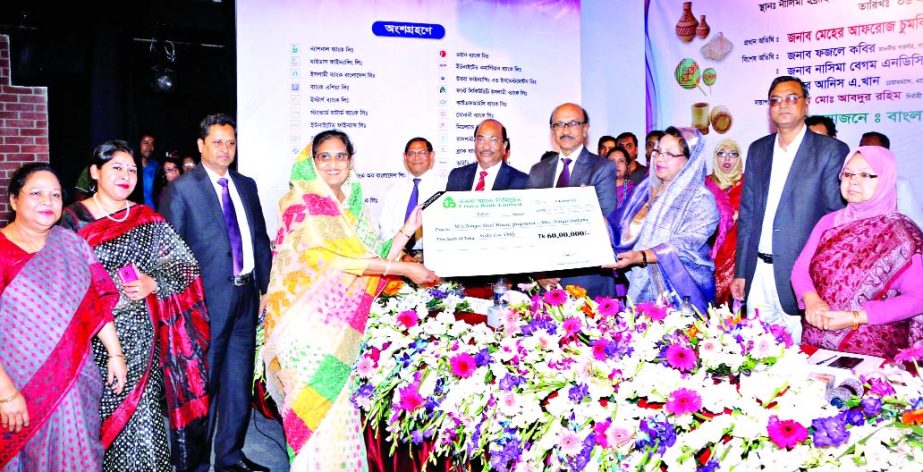 State Minister for Women and Children Affairs Ministry Meher Afroz Chumki MP, handing over a cheque to a new Women Entrepreneur financed by Uttara Bank Limited in the "Bankers-SME Nari Uddogta Somabesh and Ponya Prodorshoni Mela 2017" at a city auditori