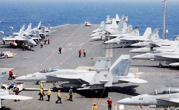 US Navy personnel prepare to launch an F18 fighter jet on the deck of USS Carl Vinson.