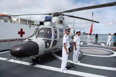 Members of the Chinese People Liberation Army Navy stand by a helicopter on the PLA(N) ship Haikou as it sits docked at Joint Base Pearl Harbor Hickam in Honolulu, Hawaii