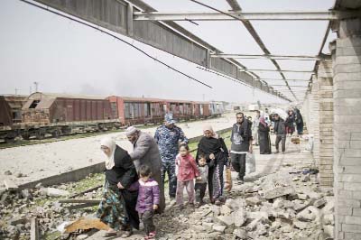 Iraqi civilians flee through a destroyed train station during fighting between Iraqi security forces and Islamic State militants, on the western side of Mosul, Iraq on Sunday