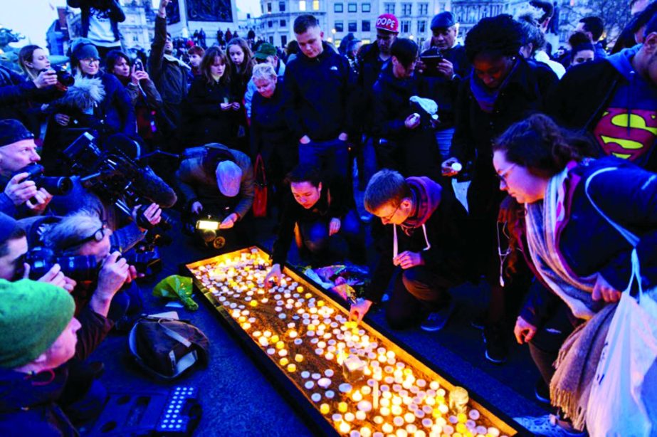 People light candles on a patch of sand during a vigil in Trafalgar Square in central London.