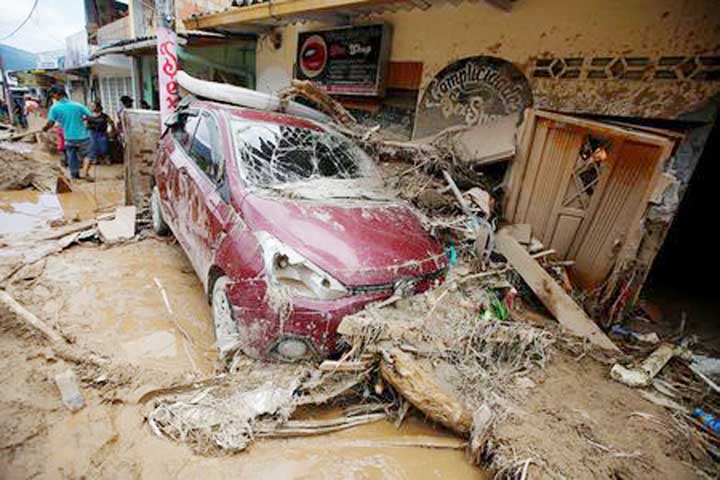 People remove debris from a destroyed street after flooding and mudslides caused by heavy rains leading several rivers to overflow, pushing sediment and rocks into buildings and roads, in Mocoa.