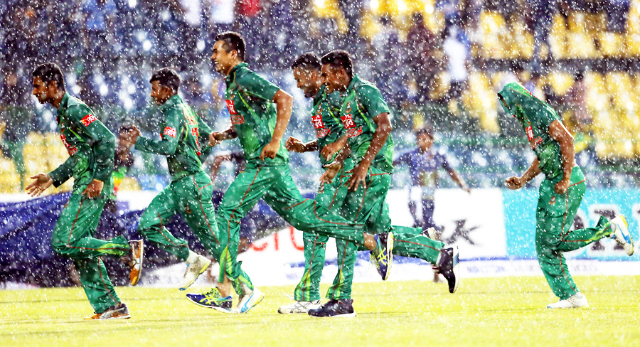 Players of Bangladesh cricket team run back to the pavilion, prompted by a sudden downpour during the 1st T20I between Sri Lanka and Bangladesh at Colombo on Tuesday.