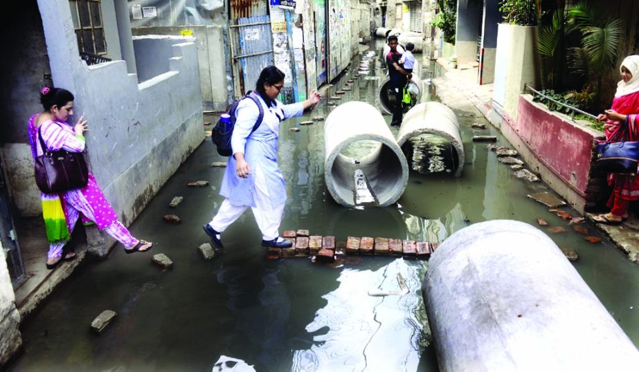 RESIDENTS' WOES KNOW NO BOUND: The residents of Daktar Goli at Malibagh area in the capital, including school and college-going girls, have long been struggling to cross this narrow lane as a number of unused sewerage line pipes are left on the lane by c