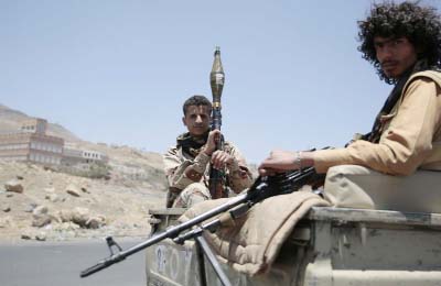 Shiite fighters, known as Houthis, secure a road, as people take part in a march, denouncing plans by the Arab coalition to attack Hodeidah, from Sanaa to the port city of Hodeidah, Yemen on Wednesday.