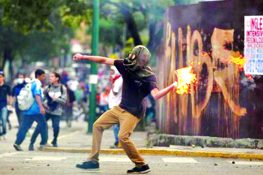 A demonstrator throws a molotov cocktail during clashes with riot police while rallying against Venezuela's President Nicolas Maduro in Caracas, Venezuela.