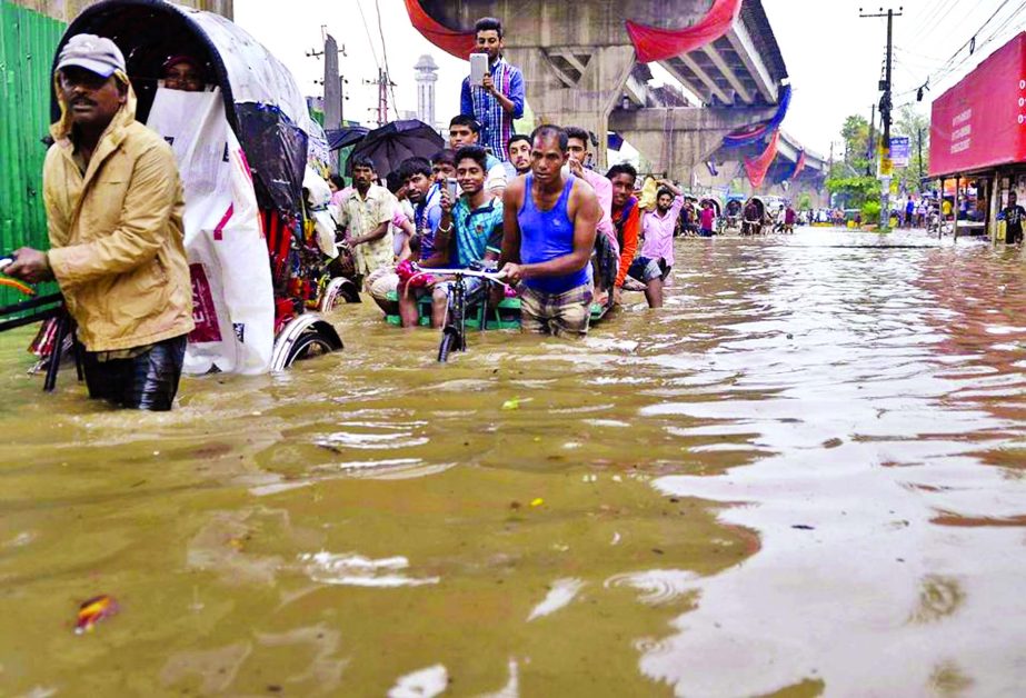 Many streets of low-lying areas in Port city Chittagong went under thigh deep water due to torrential rains as rickshaw-van pullers are struggling to cross the flood waters. This photo was taken from busy Jubilee Road on Friday.