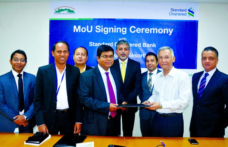 Makam E Mahmud Billah, Head of Retail Products of Standard Chartered Bank and Nazim Shafkat Choudhury, Director of Nazimgarh Resorts in Sylhet exchanging a MoU signing documents in the city recently. Under the deal, the resorts will provide a range of exc
