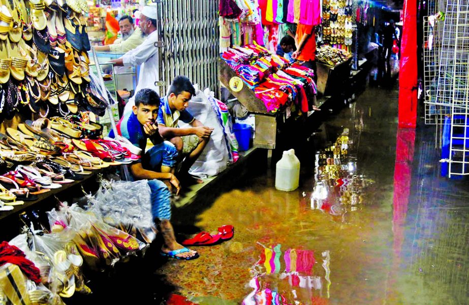 Shopowners passing idle time for the lack of buyers as the premises of shops were submerged by the rain water. The snap was taken from Mouchak Market in the city on Monday.