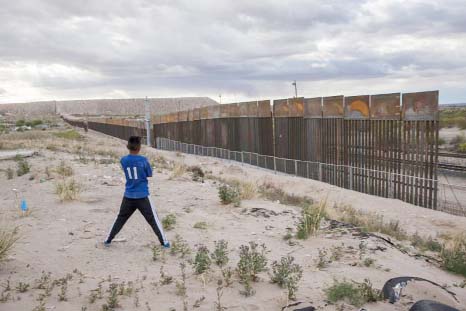 A youth looks at a new, taller fence being built along U.S.-Mexico border, replacing the shorter, gray metal fence in front of it, in the Anapra neighborhood of Ciudad Juarez, Mexico, across the border from Sunland Park, New Mexico.