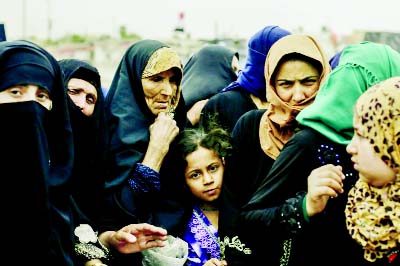 Mosul residents wait at a food distribution point inside western Mosul, Iraq.