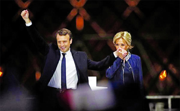 Frence's youngest President elect Emmanuel Macron and his wife Brigitte Trogneux celebrate on the stage at his victory rally near the Louvre in Paris on Sunday. Internet photo