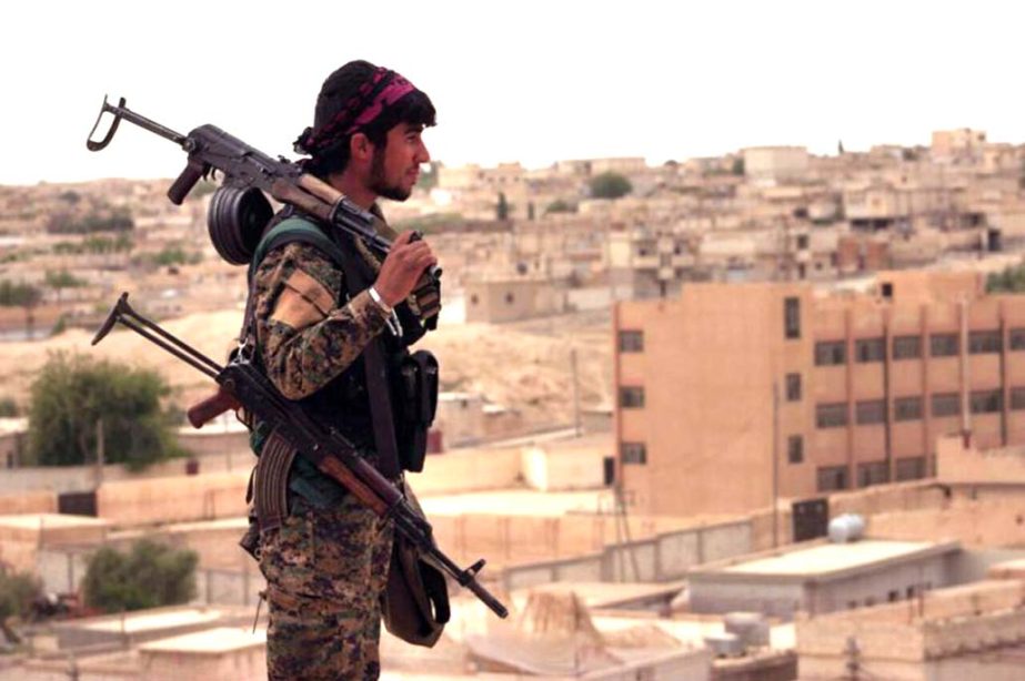 Syria Democratic Forces (SDF), shows a fighter from the SDF carrying weapons as he looks toward the northern town of Tabqa, Syria.