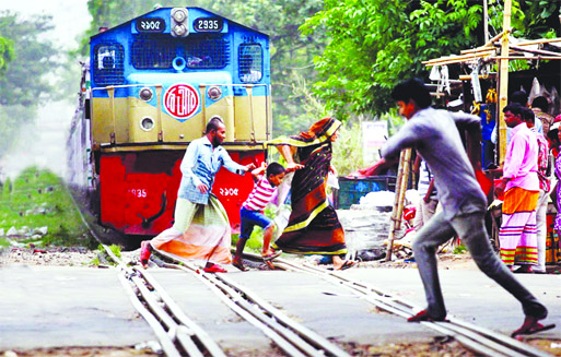 Crossing railway line along with family members including women and children, even when a train is fast approaching is a regular feature at city's different points. Photo shows how a man risking the lives of his kid and wife making a desperate dash to c