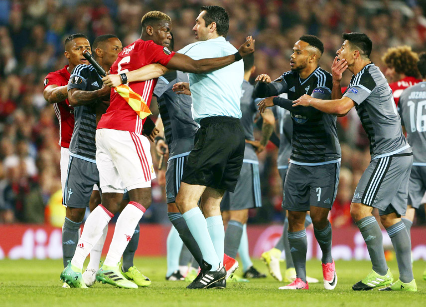 Manchester United's Paul Pogba (left) is involved in a dispute, as an assistant referee holds him back during the Europa League semifinal second leg soccer match between Manchester United and Celta Vigo at Old Trafford in Manchester, England on Thursday.